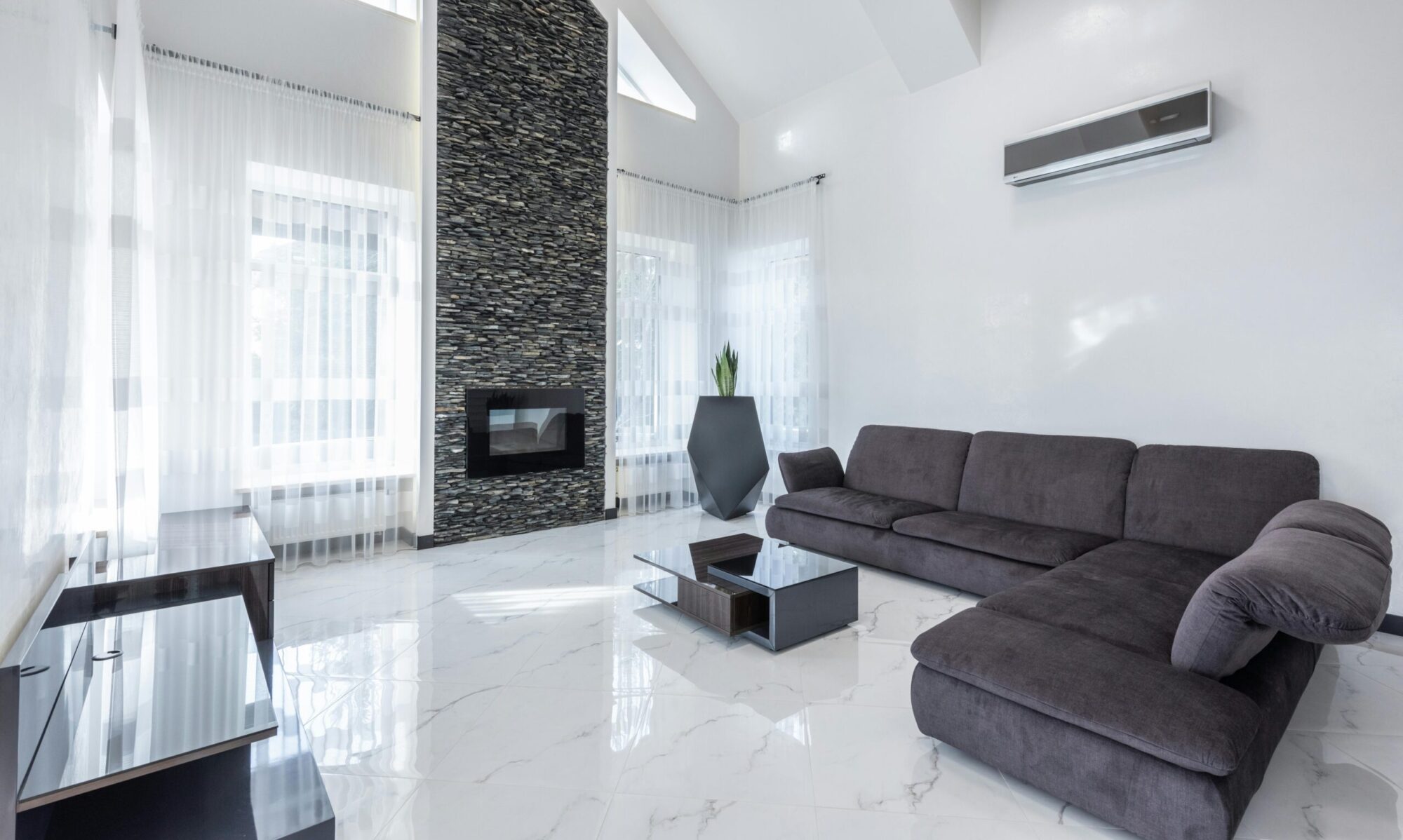 Elegant modern living room featuring a stone fireplace, sleek furniture, and airy ambiance.